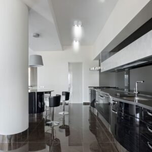 Μοντέρνα μαύρα ντουλάπια κουζίνας με γυαλιστερό φινίρισμα και ανοξείδωτες συσκευές σε πολυτελή κουζίνα.