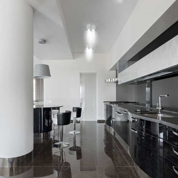 Μοντέρνα μαύρα ντουλάπια κουζίνας με γυαλιστερό φινίρισμα και ανοξείδωτες συσκευές σε πολυτελή κουζίνα.