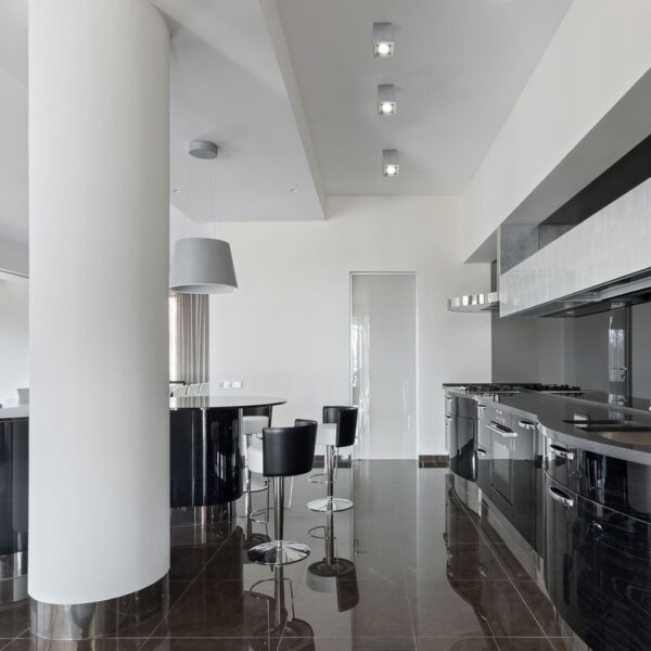 Μοντέρνα κουζίνα με γυαλιστερό μαύρο φινίρισμα και νησίδα με μαύρα ψηλά σκαμπό, ιδανική για σύγχρονα σπίτια.