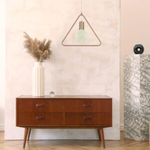 Σκανδιναβικό σαλόνι με ξύλινη συρταριέρα, μοντέρνο φωτιστικό και βάζο με αποξηραμένα λουλούδια.